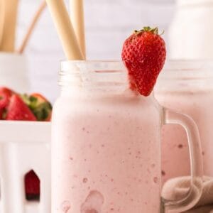 mason jar with a strawberry milkshake inside.