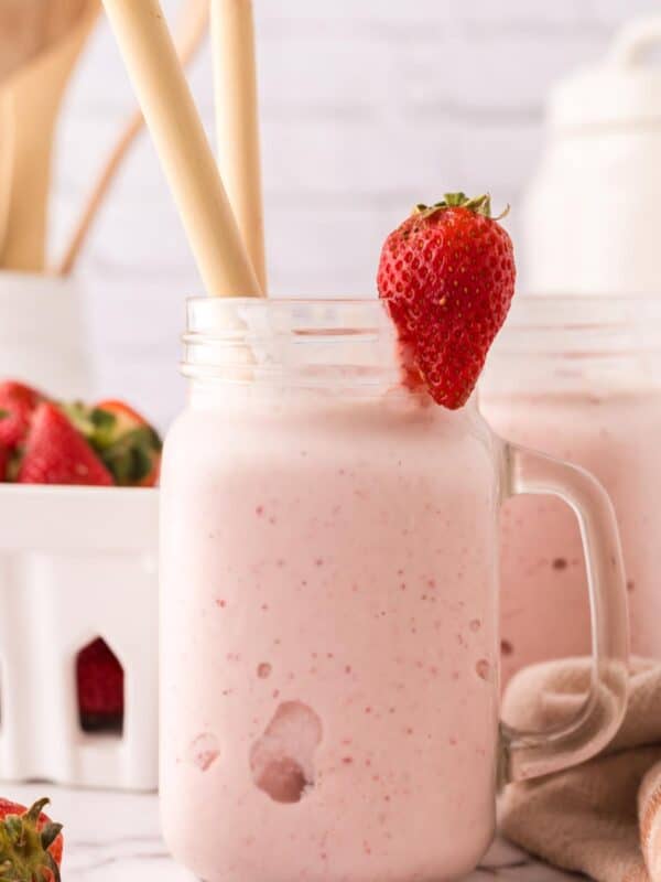 mason jar with a strawberry milkshake inside.