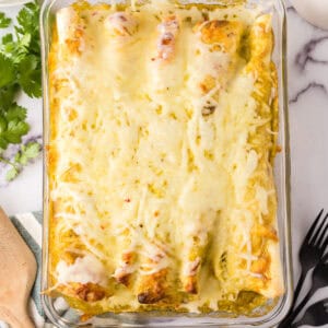 cheesy and gooey tomatillo ranch burritos in a clear casserole dish.
