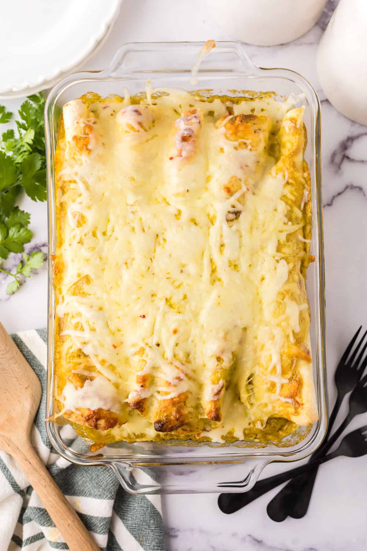 cheesy and gooey tomatillo ranch burritos in a clear casserole dish.