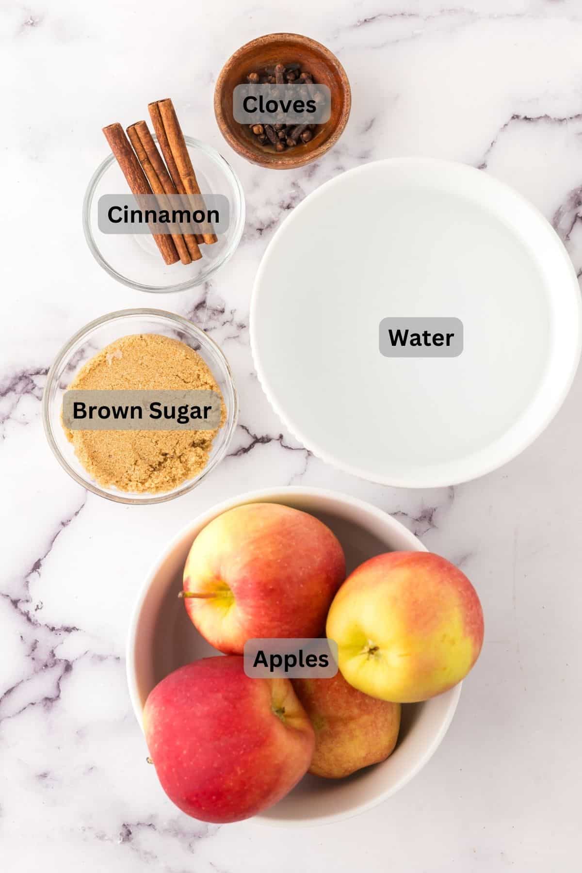 portion bowls each with digitally labeled raw ingredients to make Slow Cooker Apple Cider.