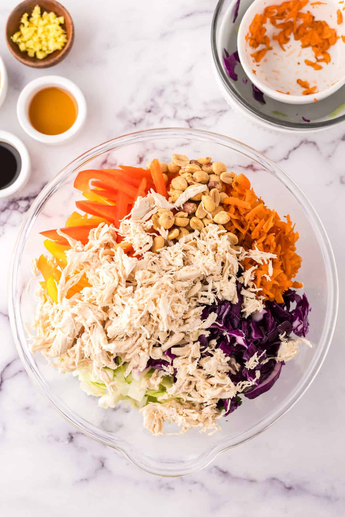 clear mixing bowl in the process of making asian chicken salad with peanut dressing.