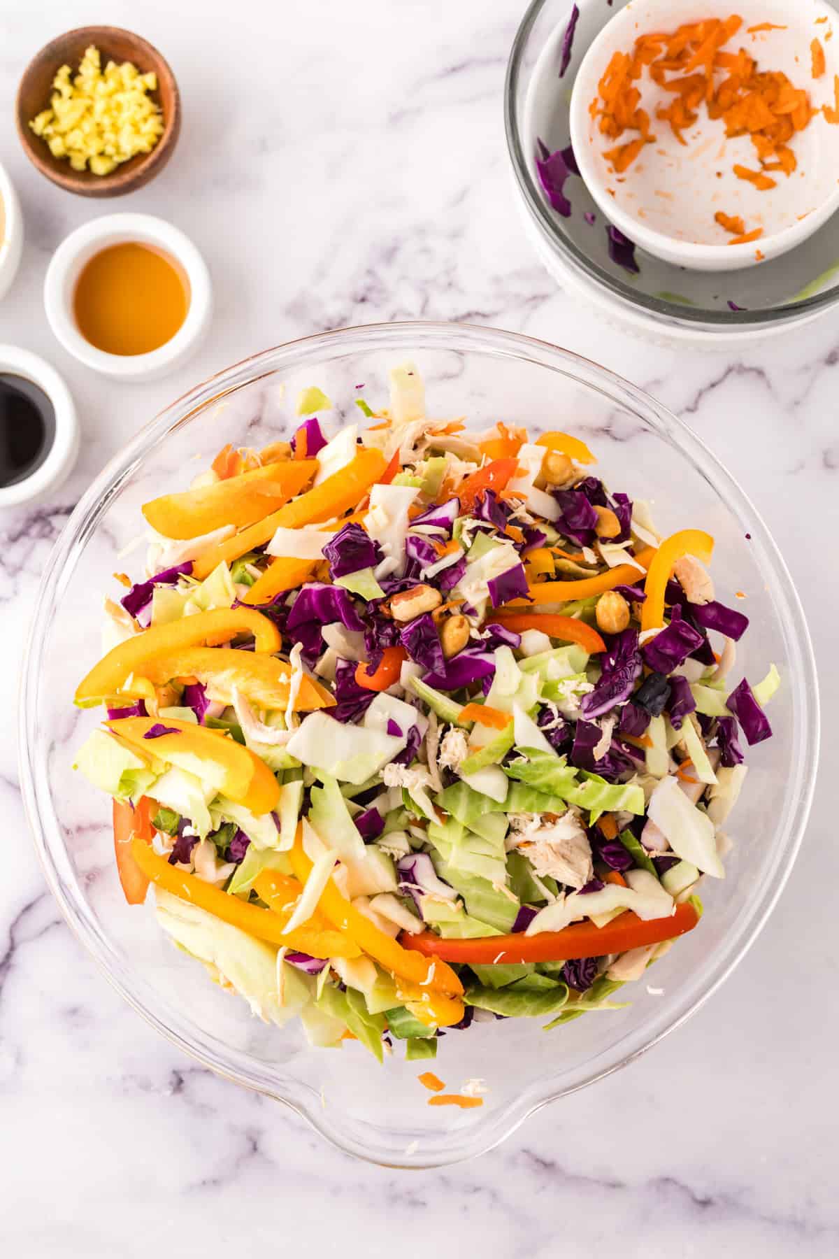 clear mixing bowl in the process of making asian chicken salad with peanut dressing.