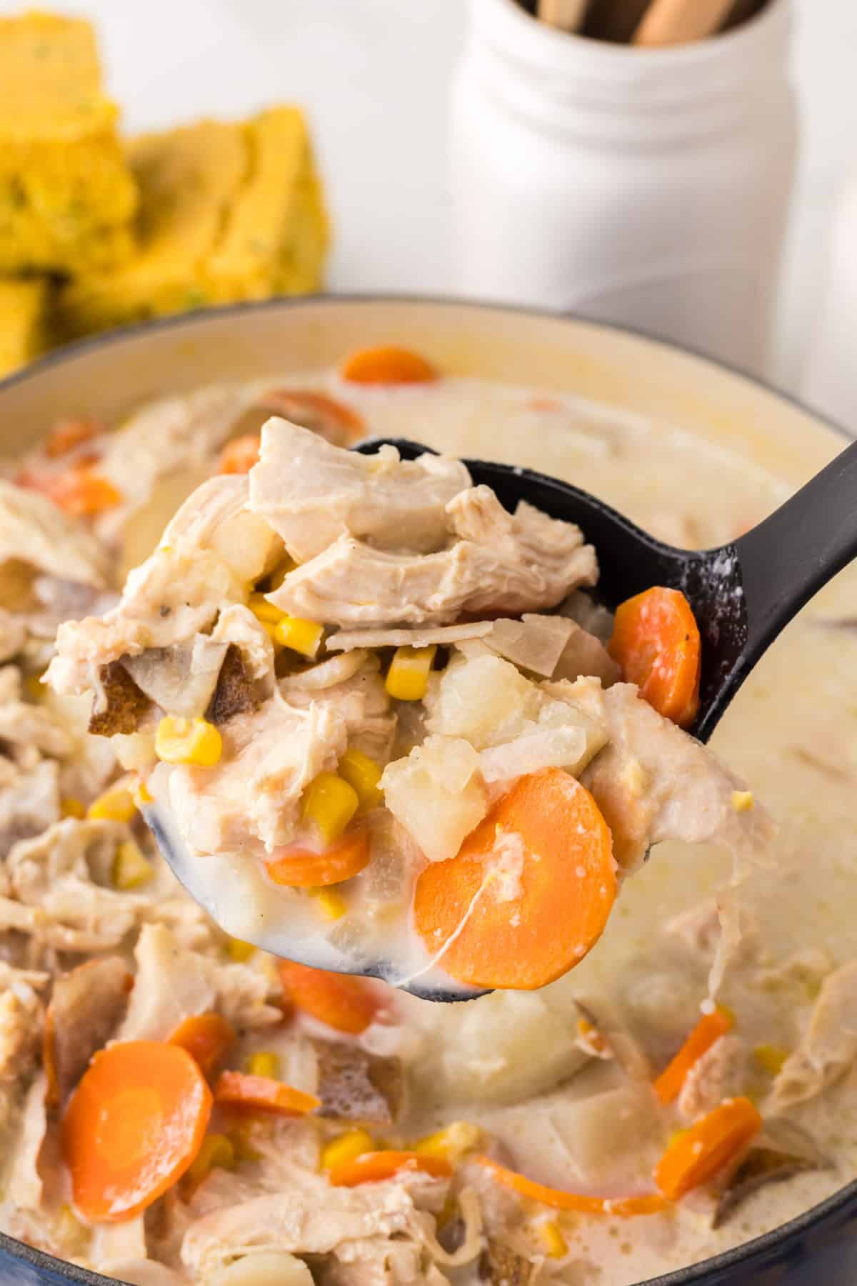 big dutch oven with baked potato corn chowder with a ladle.