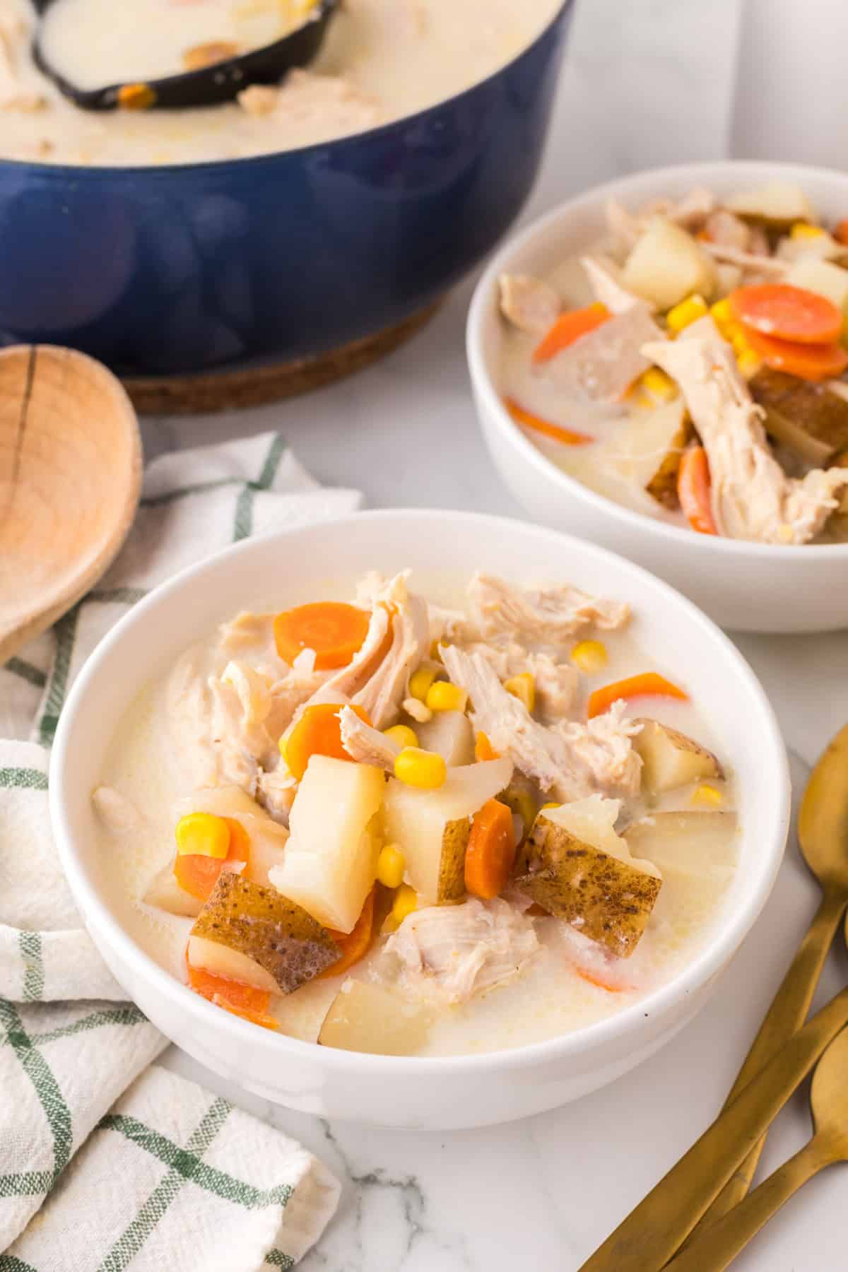 two white serving bowls of baked potato corn chowder.