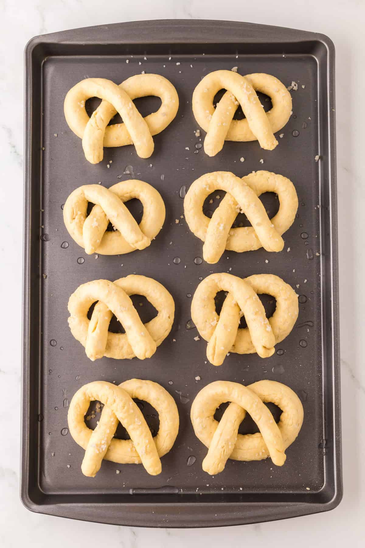 baking dish with raw big soft pretzels.