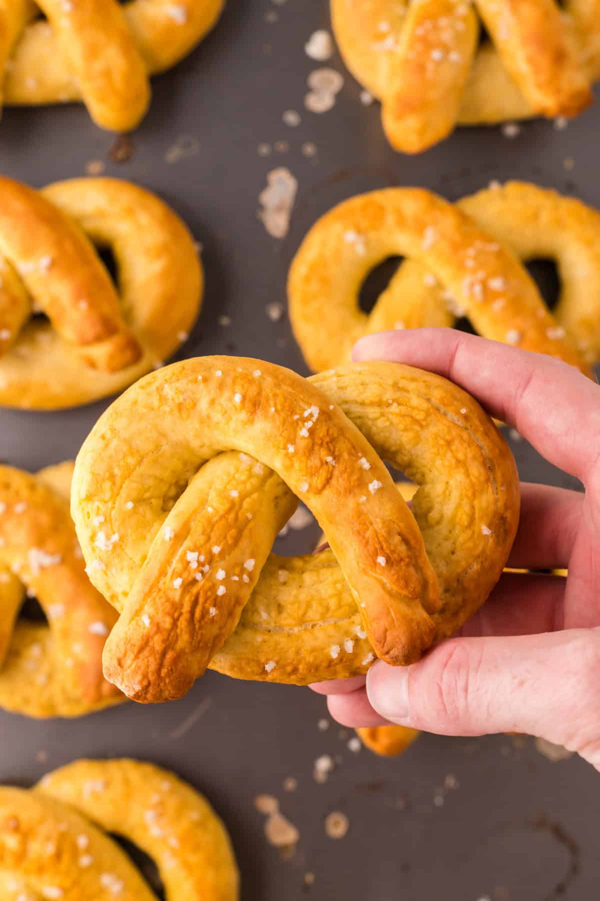 POV hand holding a big soft pretzel.