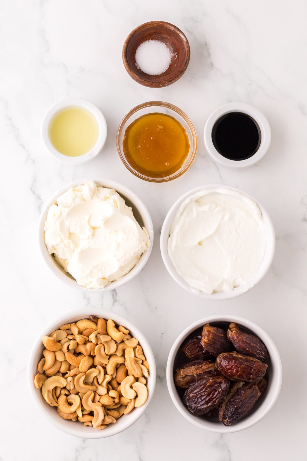 portion bowls each with raw ingredients to make healthy no-bake cheesecake recipe.