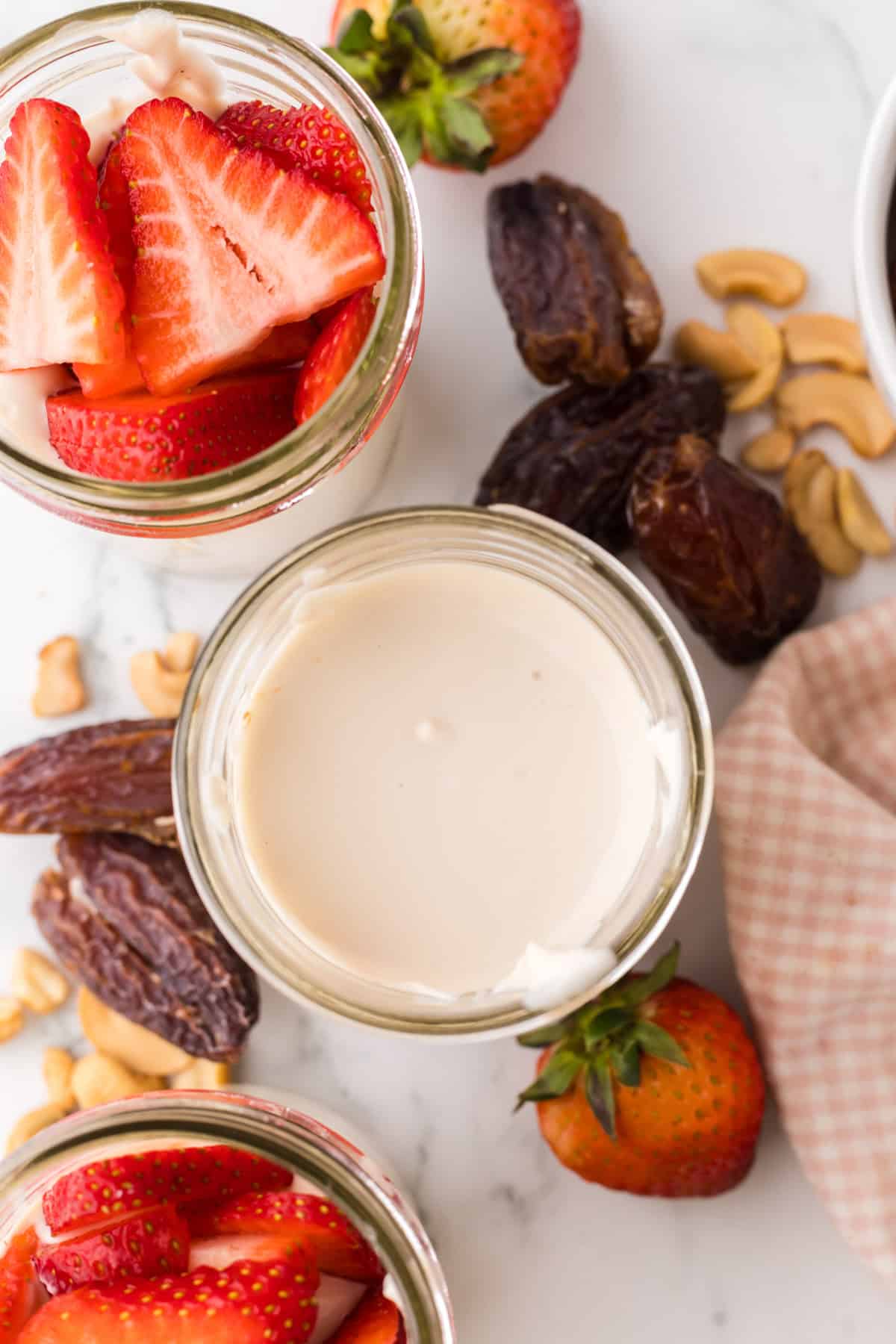 healthy no-bake cheesecake layered into a wide mouthed mason jar with fresh strawberries on top.