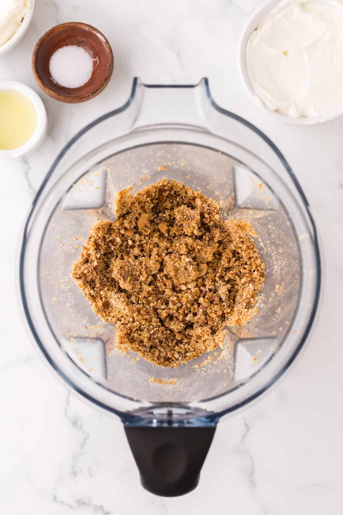 blender with ingredients for the bottom crust of the healthy no-bake cheesecake recipe.