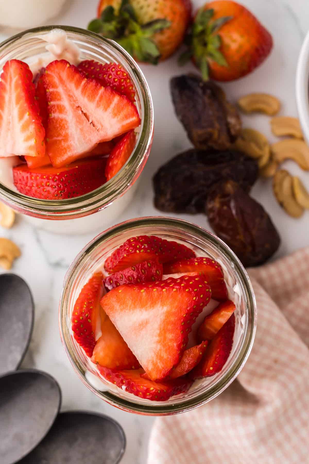 healthy no-bake cheesecake layered into a wide mouthed mason jar with fresh strawberries on top.