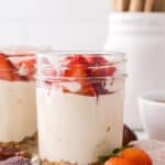 healthy no-bake cheesecake layered into a wide mouthed mason jar with fresh strawberries on top.