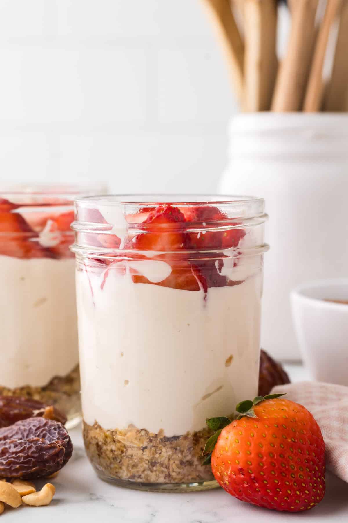 healthy no-bake cheesecake layered into a wide mouthed mason jar with fresh strawberries on top.