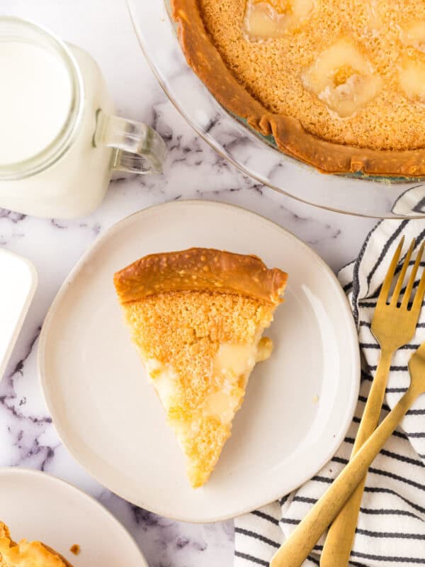 hoosier sugar cream pie slice on a round white plate next to a glass of milk.