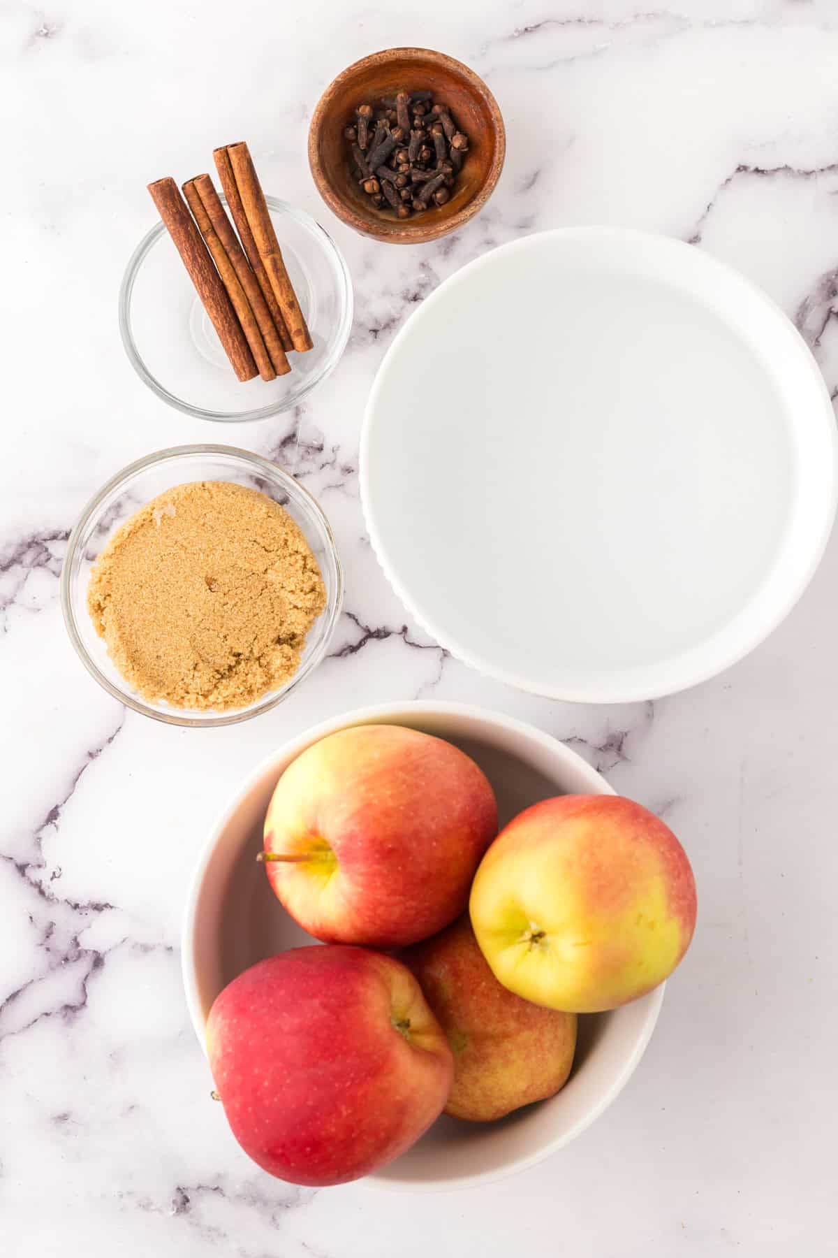 portion bowls each with raw ingredients to make slow cooker apple cider.