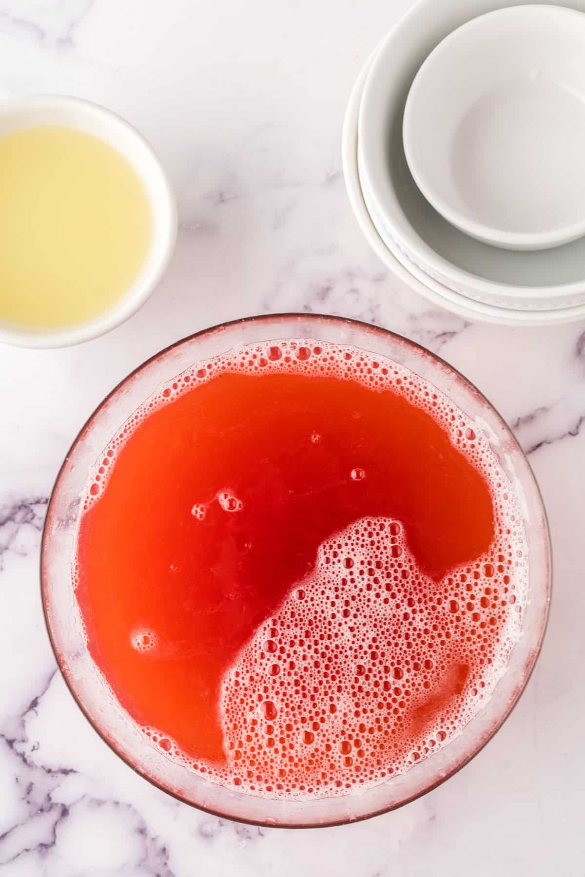 clear mixing bowl of strawberry rhubarb lemonade.