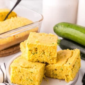 square slices of zucchini cornbread stacked on a round plate.