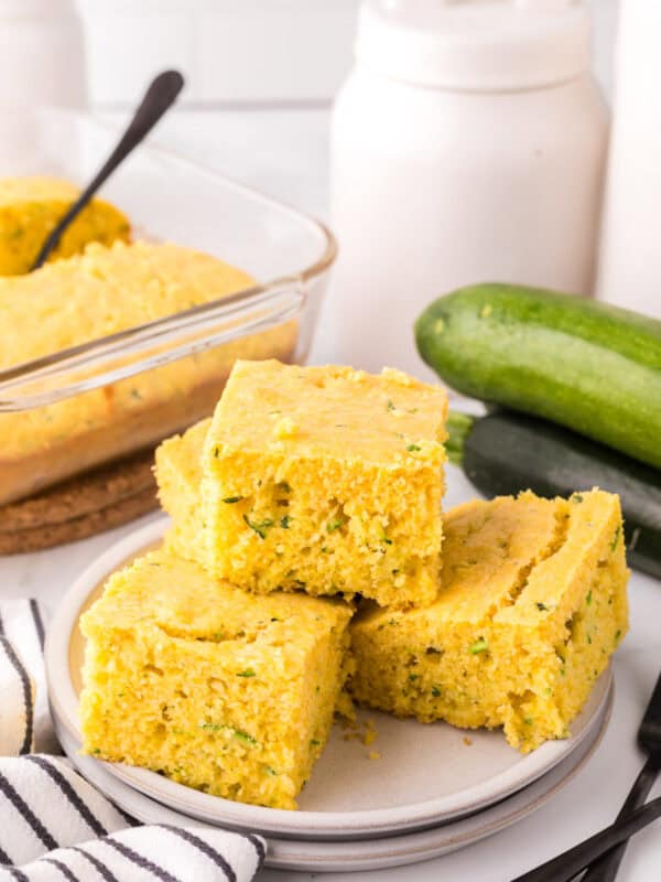 square slices of zucchini cornbread stacked on a round plate.