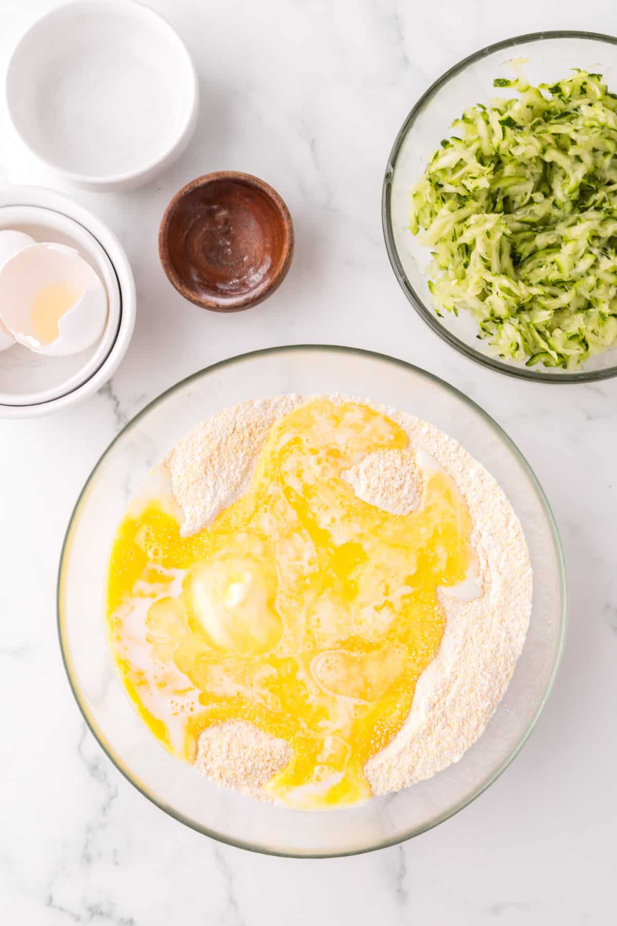 clear mixing bowl in the process of making zucchini cornbread.