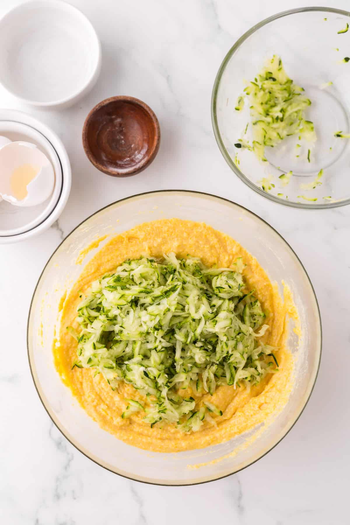 clear mixing bowl in the process of making zucchini cornbread.