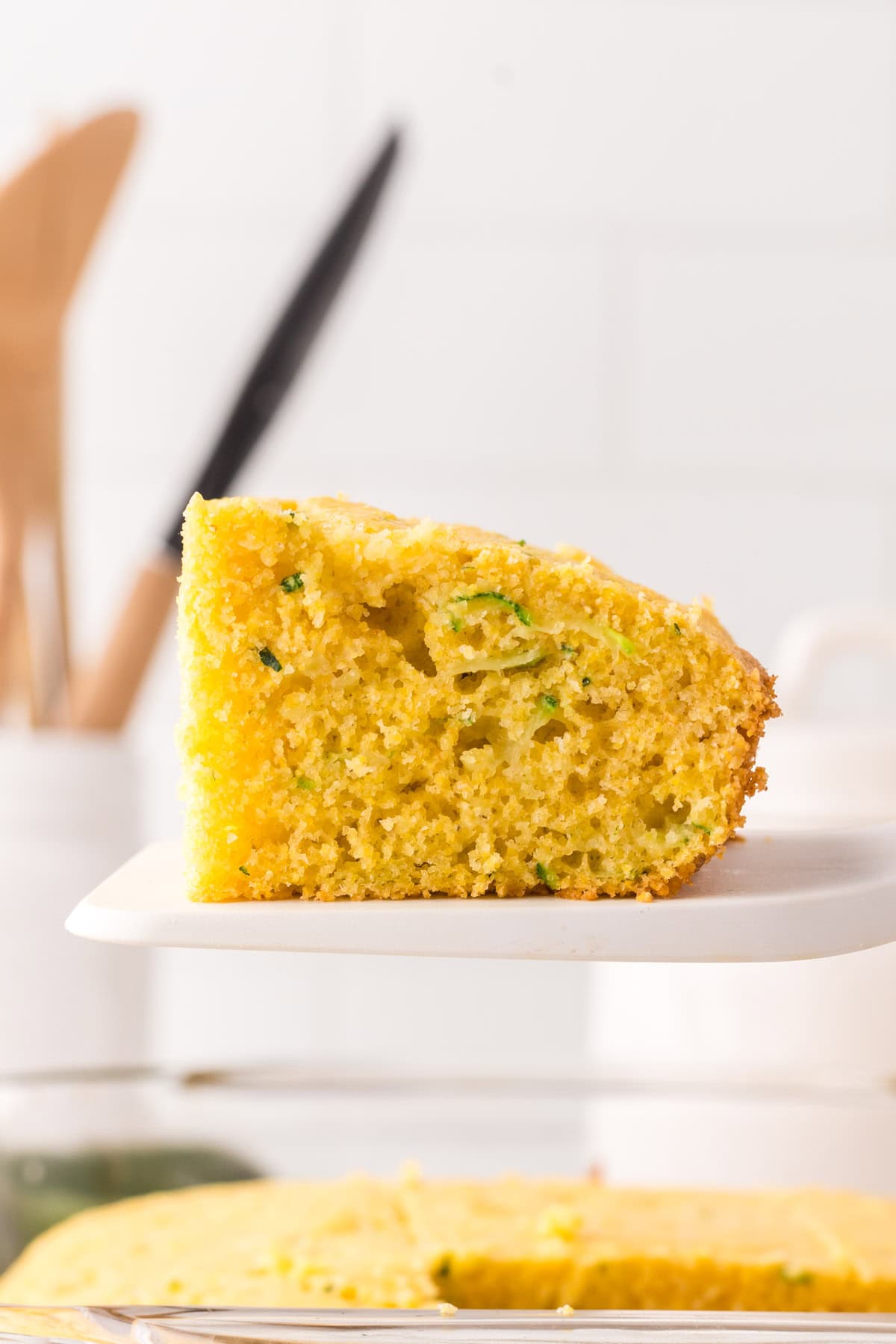 spatula holding a square slice of zucchini cornbread.