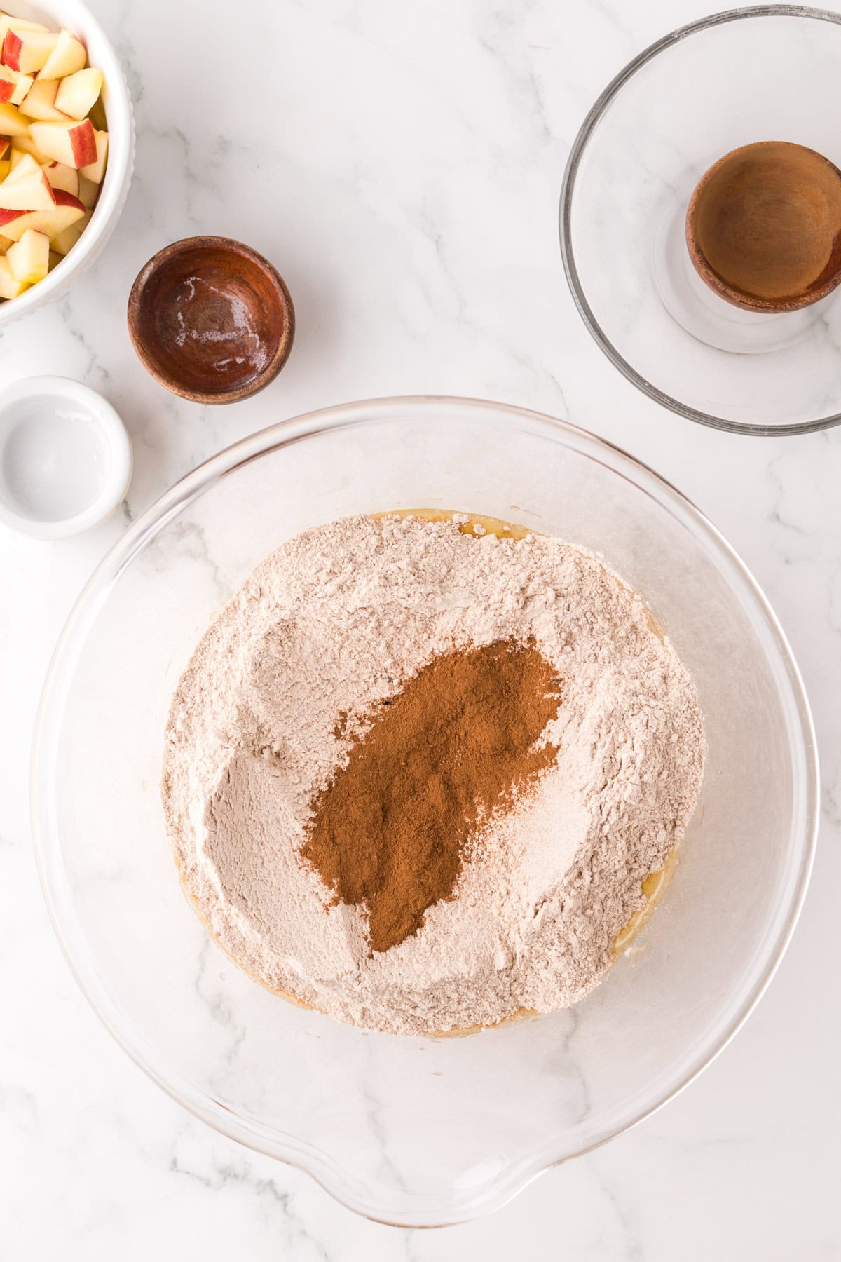 apple cake ingredients in a clear mixing bowl.