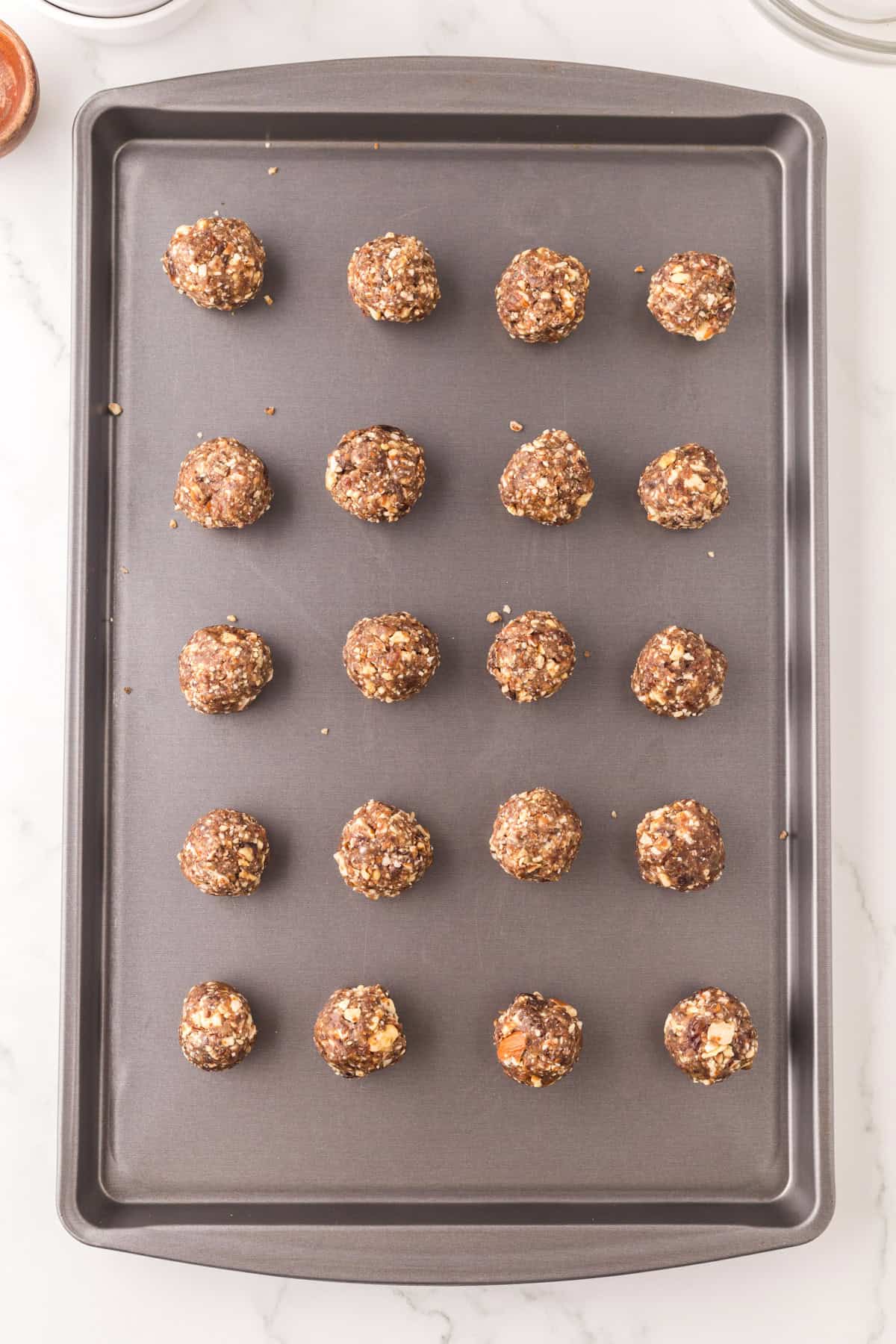 cherry energy balls in a line on a baking sheet.