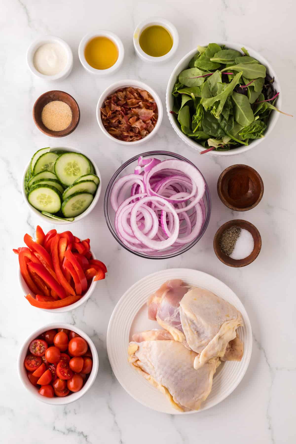 portion bowls each with raw ingredients to make chicken bacon ranch salad.