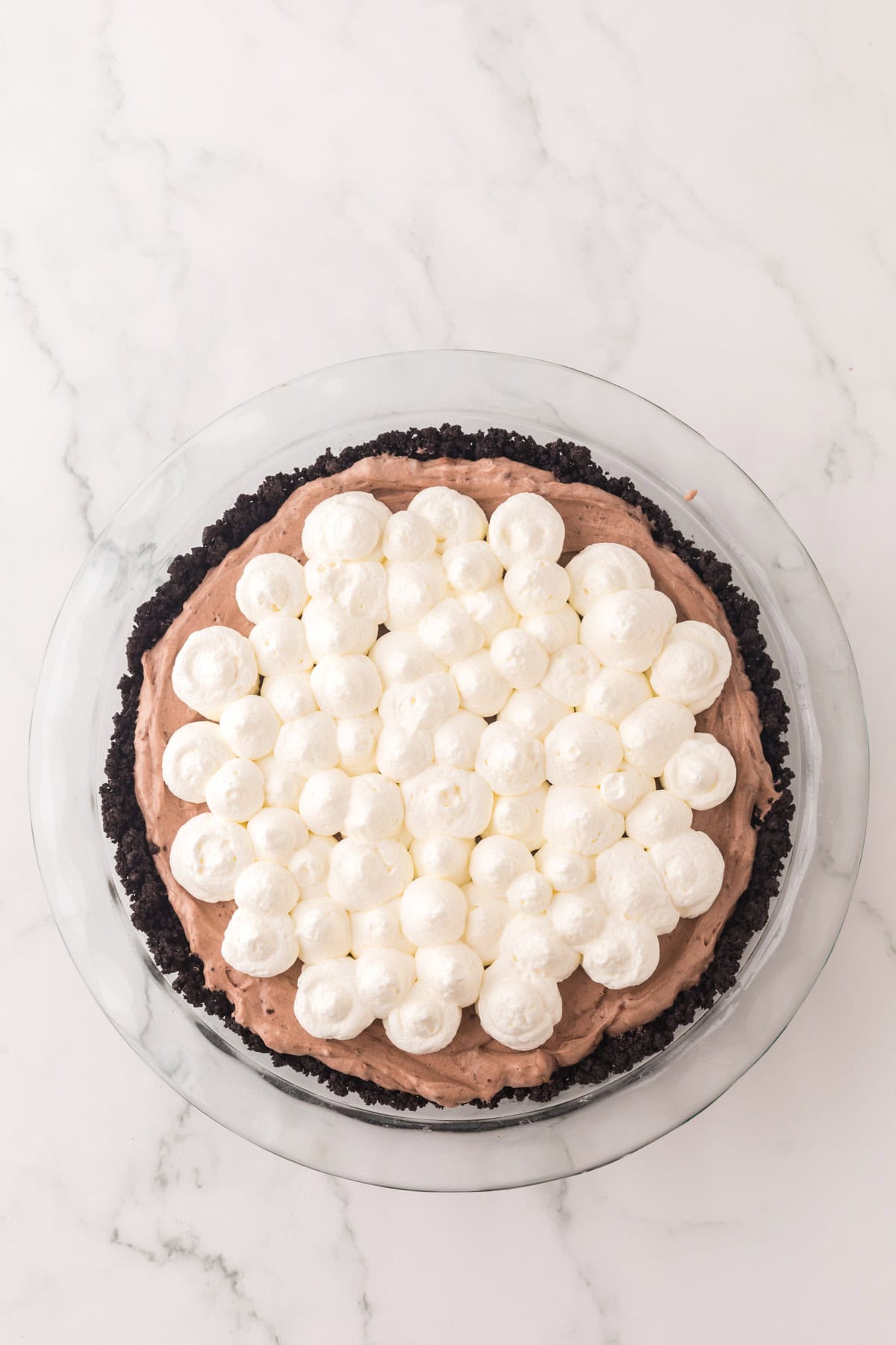 whole chocolate cream pie recipe with dollops of cream on top.