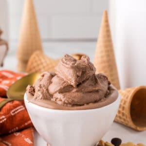 chocolate peanut butter ice cream scooped in a bowl with cones and a golden spoons around.