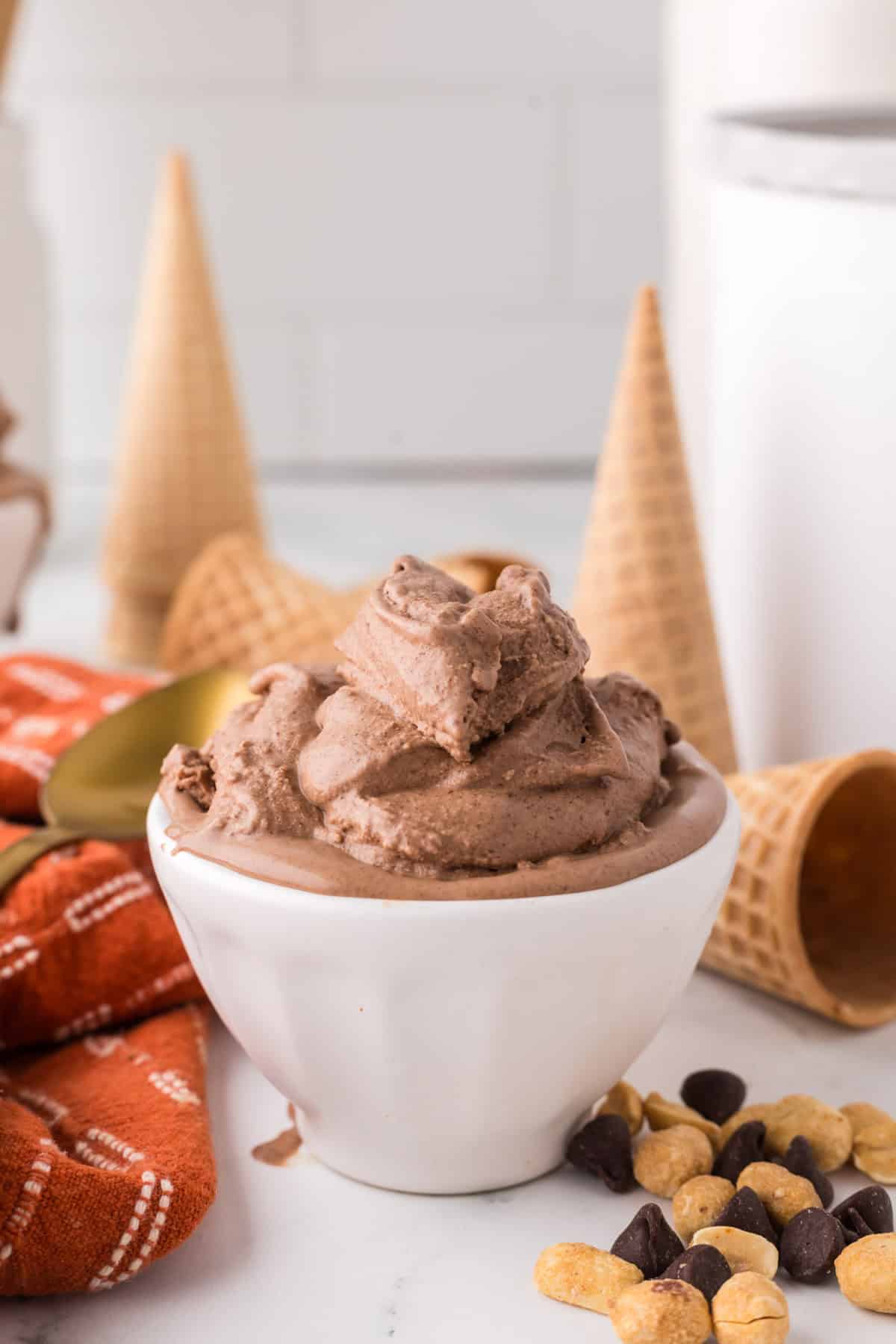 chocolate peanut butter ice cream scooped in a bowl with cones and a golden spoons around.