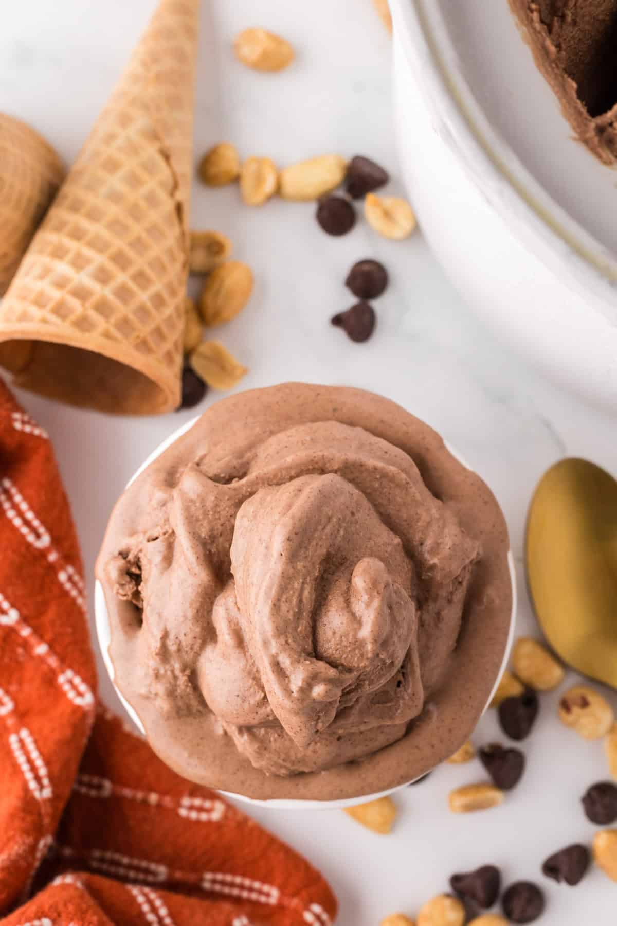 chocolate peanut butter ice cream scooped in a bowl with cones and a golden spoons around.