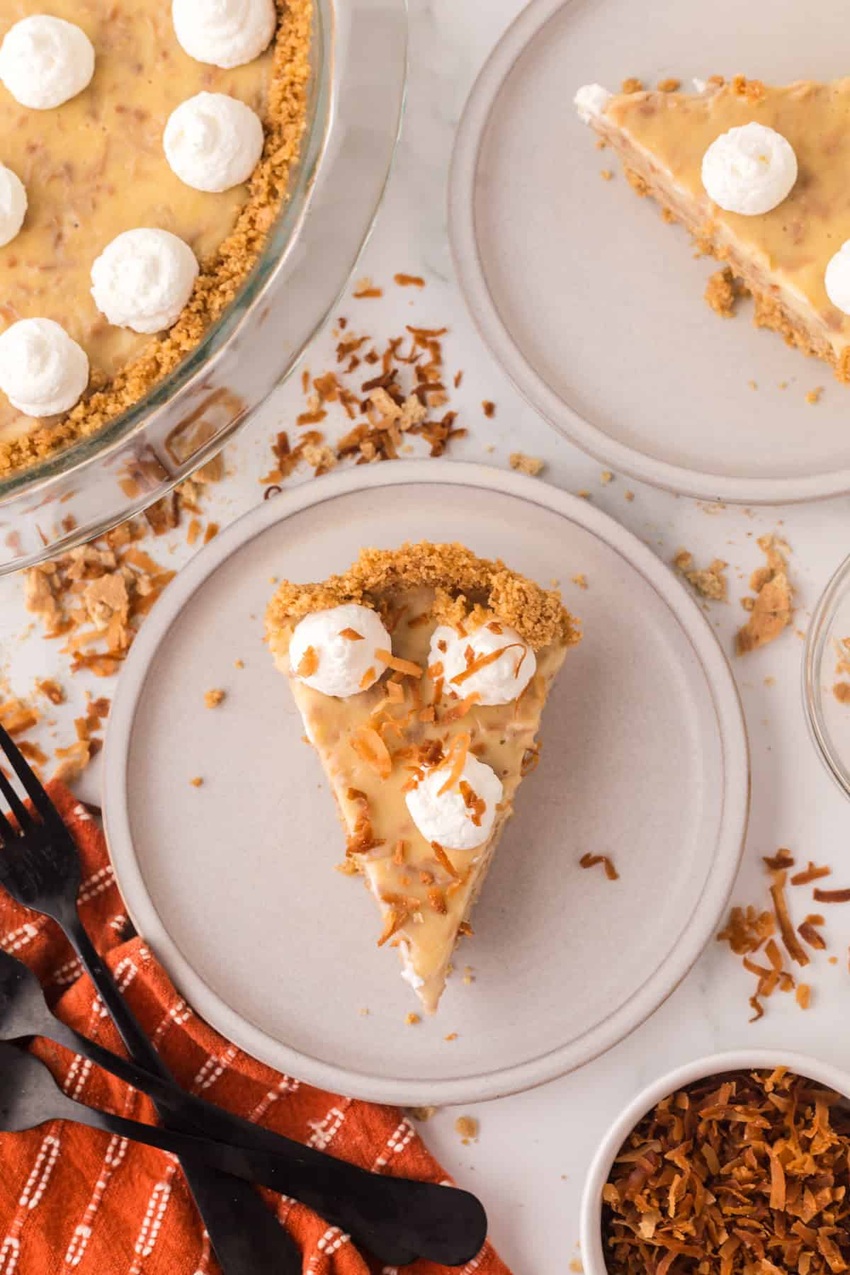 slice of coconut cream pie with dollops of cream on top on a round plate.