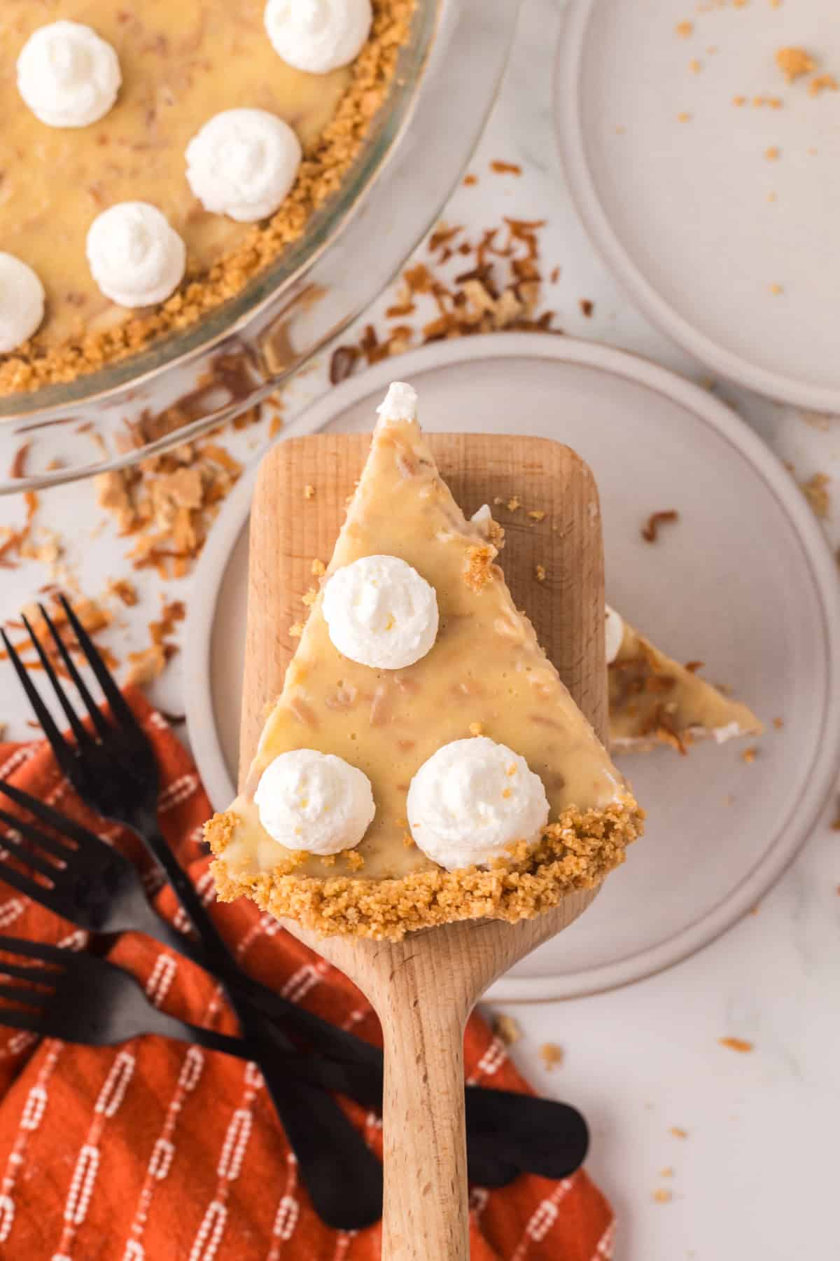 coconut cream pie recipe on a spatula over a round plate.