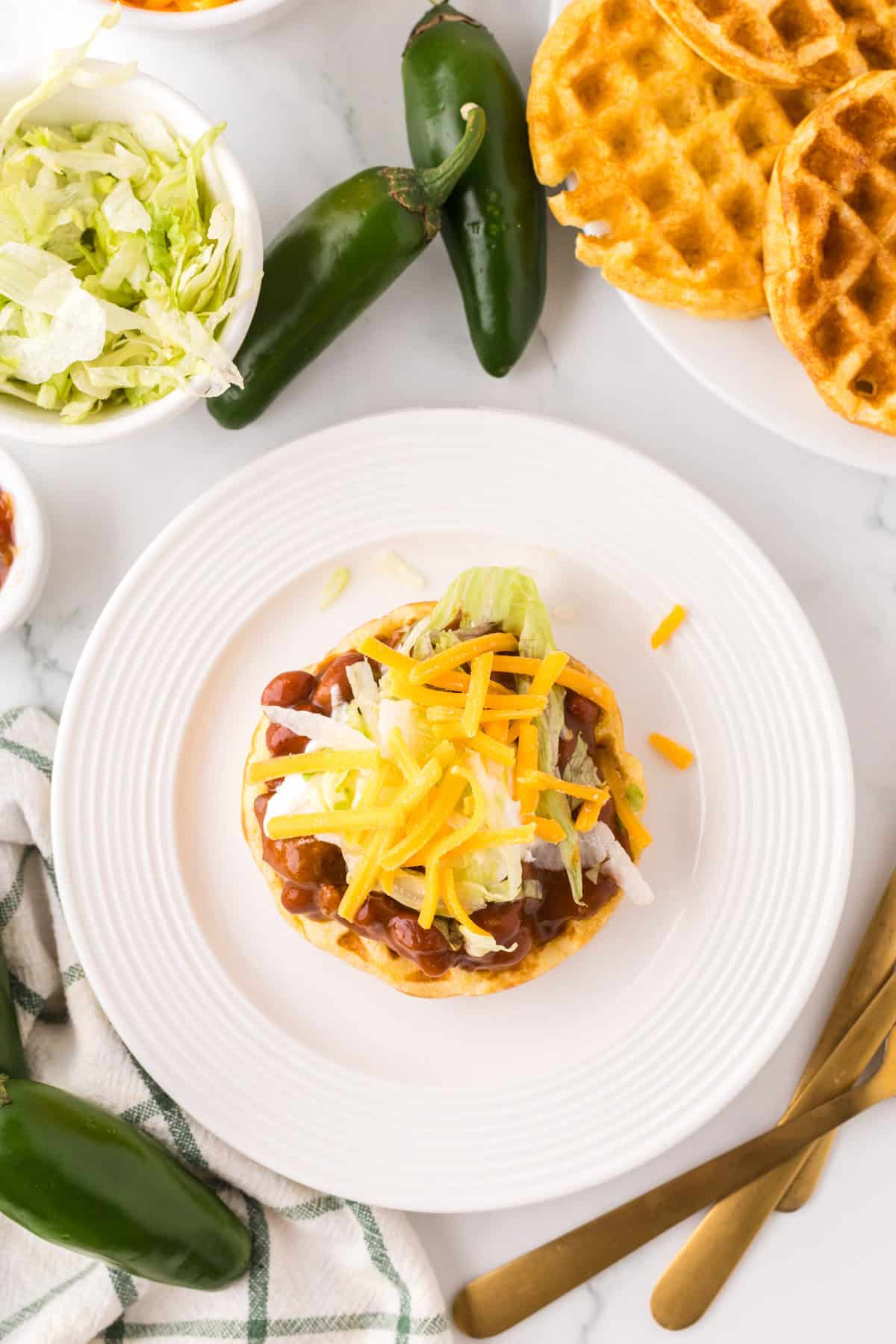 round white plate with cornbread waffles and chili.