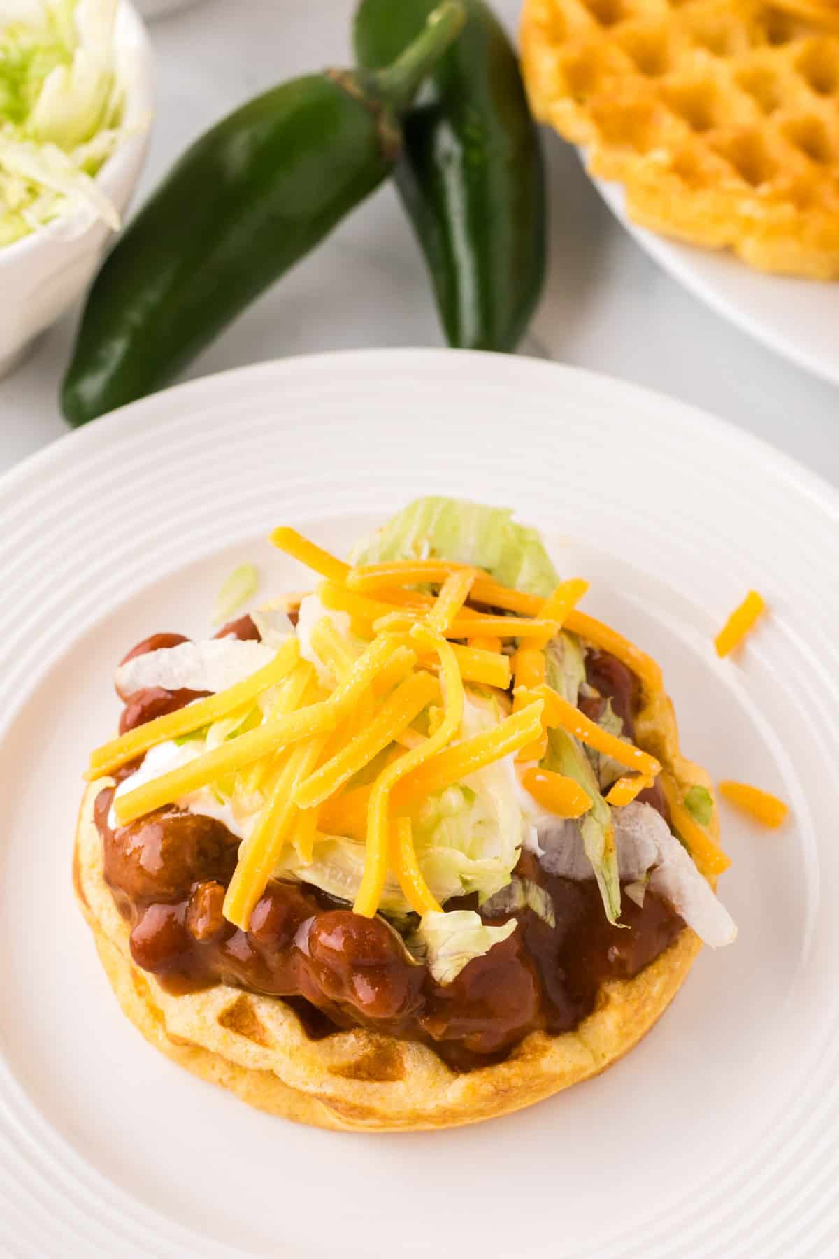 round white plate with cornbread waffles and chili.