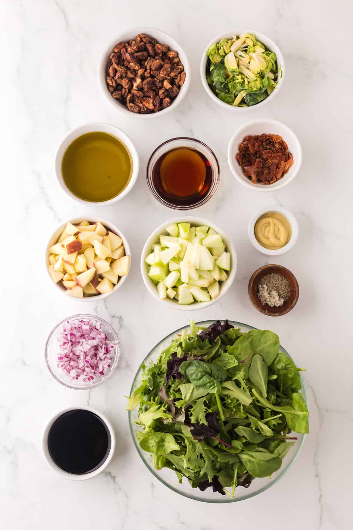 portion bowls each with raw ingredients to make fall salad with pecans and brussel sprouts recipe.