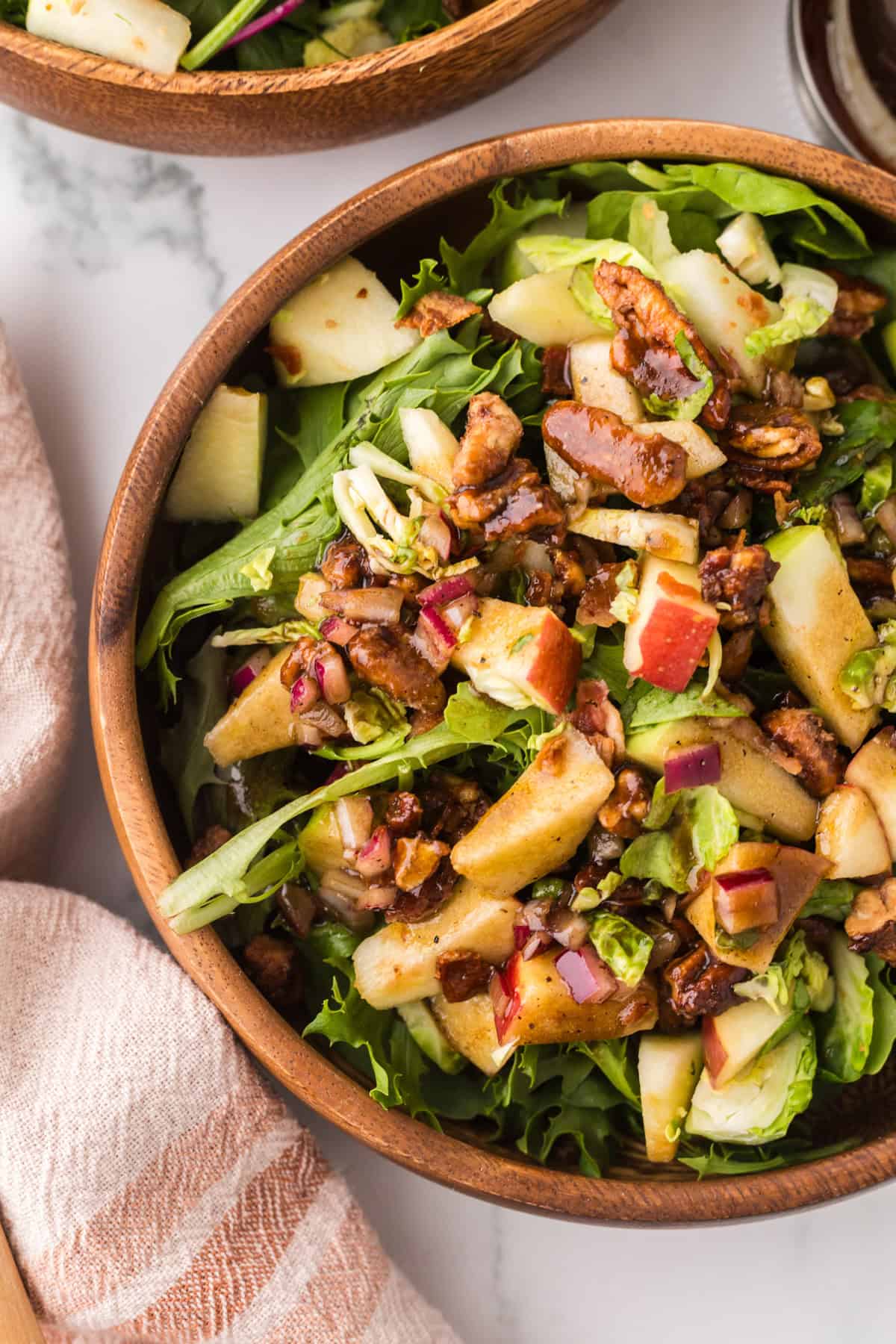 fall salad with pecan and brussel sprouts recipe in wooden mixing bowls.