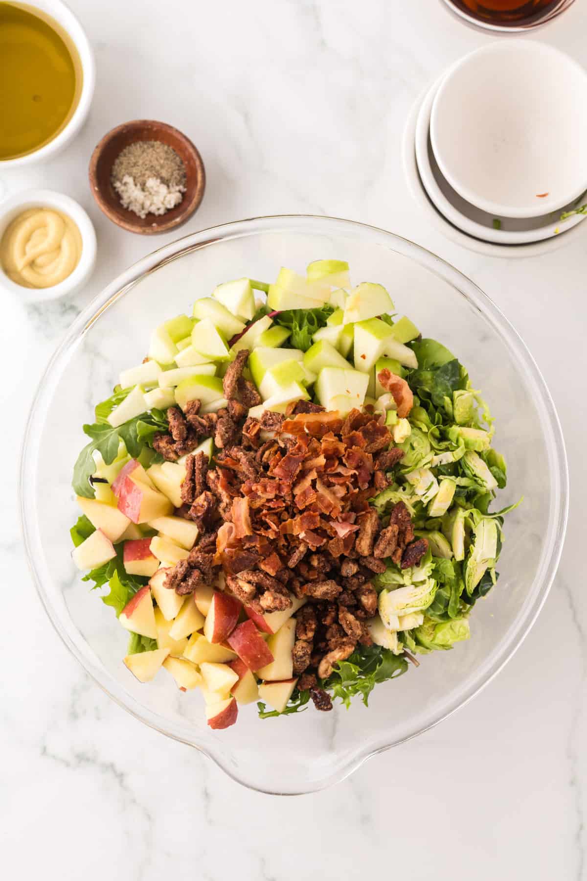 clear mixing bowl in the process of making fall salad with pecan and brussel sprouts recipe.