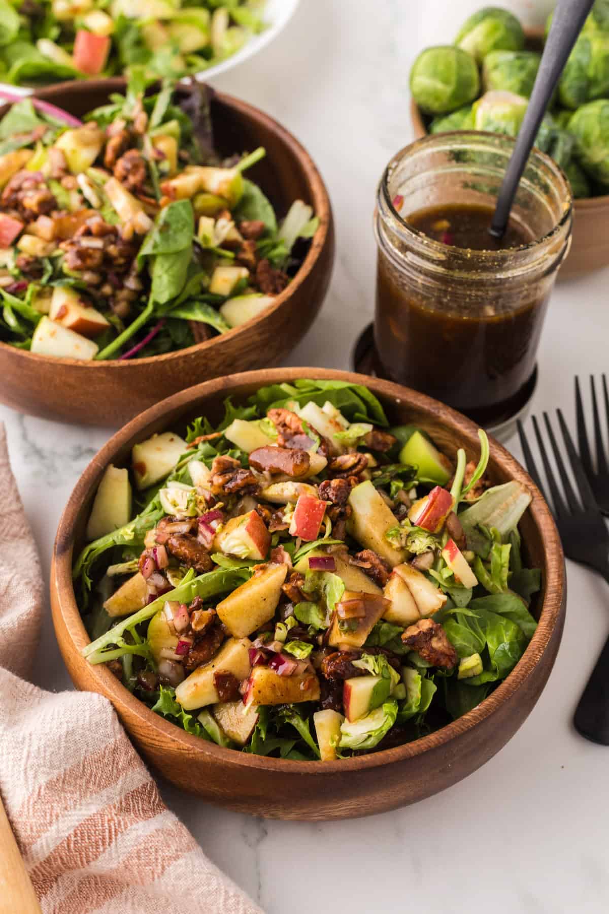 fall salad with pecan and brussel sprouts recipe in wooden mixing bowls.