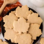 maple leaf shaped maple sugar cookies on a round black plate.