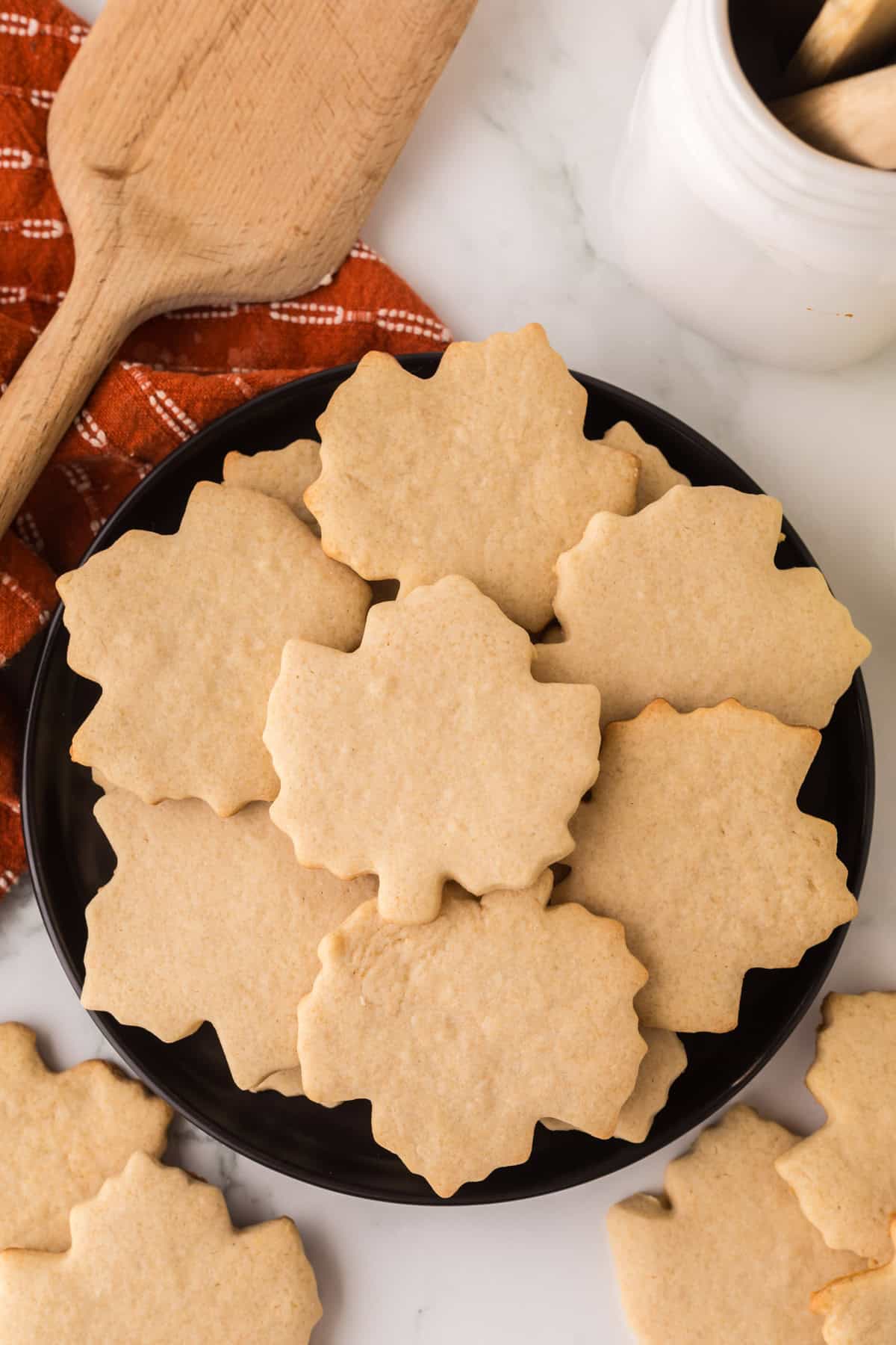 maple leaf shaped maple sugar cookies on a round black plate.