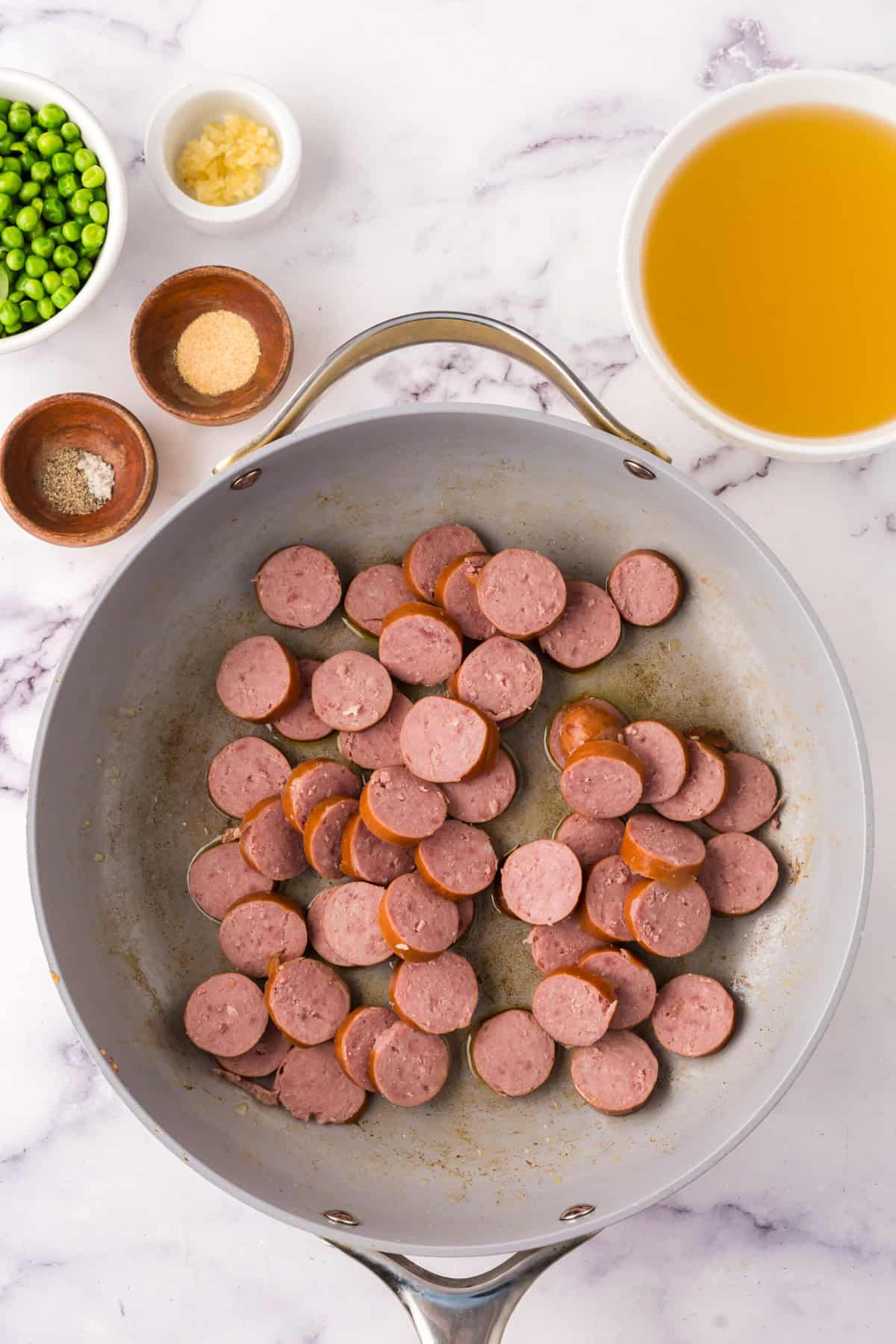 one pot sausage peas and rice in a pan in the progress of cooking.