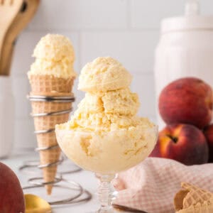 sugar cone and a stemmed glass dish with scoops of peach ice cream.