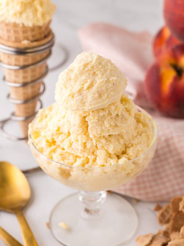 sugar cone and a stemmed glass dish with scoops of peach ice cream.