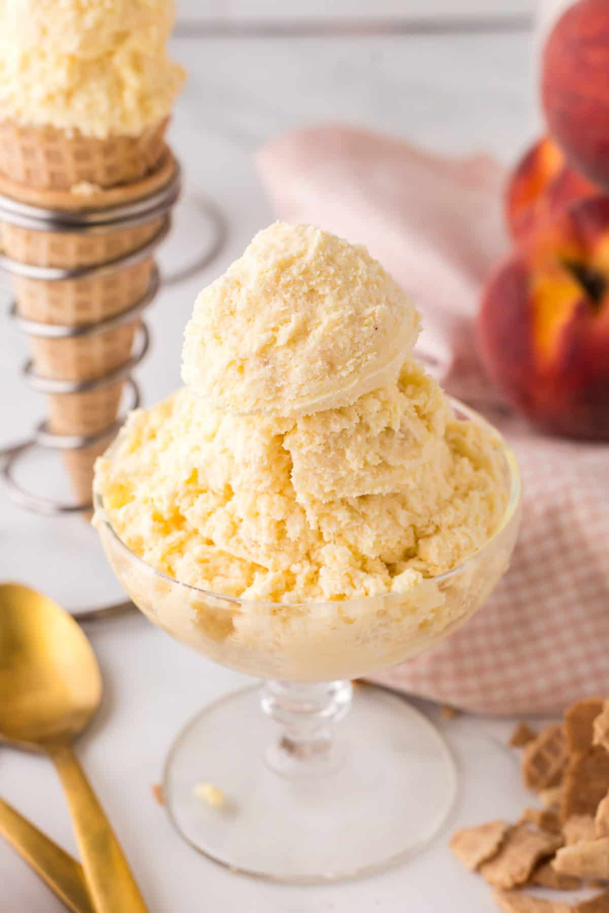 sugar cone and a stemmed glass dish with scoops of peach ice cream.