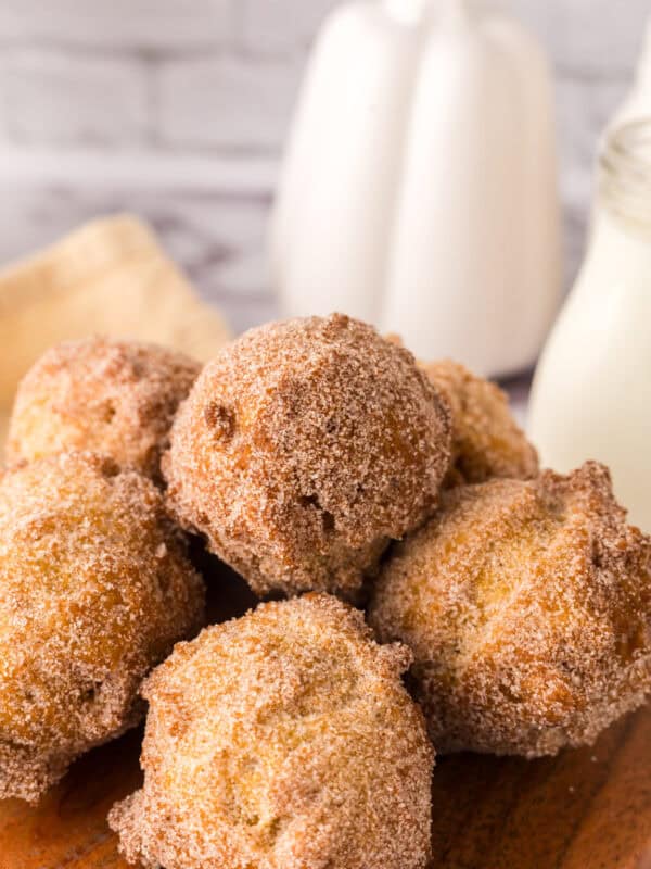 pumpkin donut holes in a pile on a wooden cutting board.