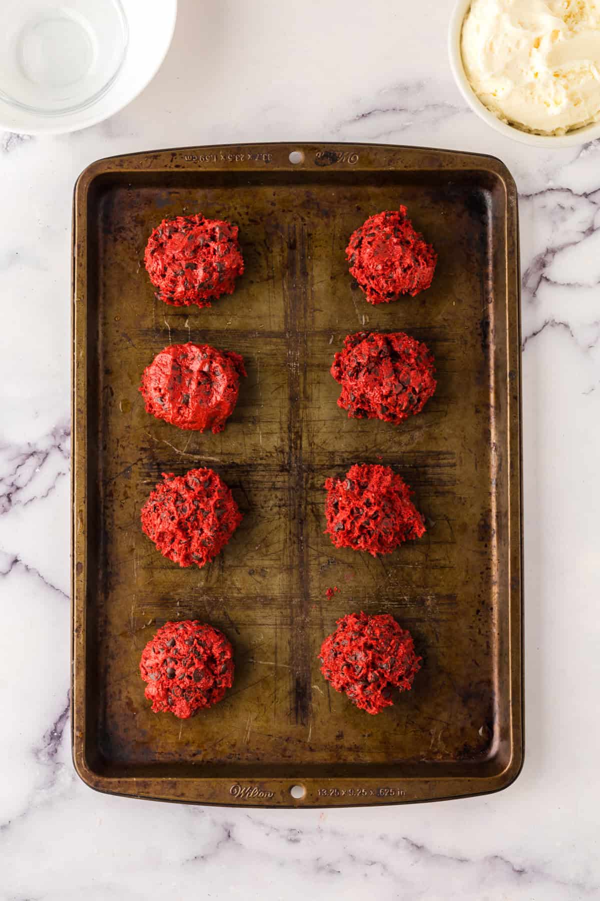 red velvet whoopee pie dough balls laid out on a baking dish.