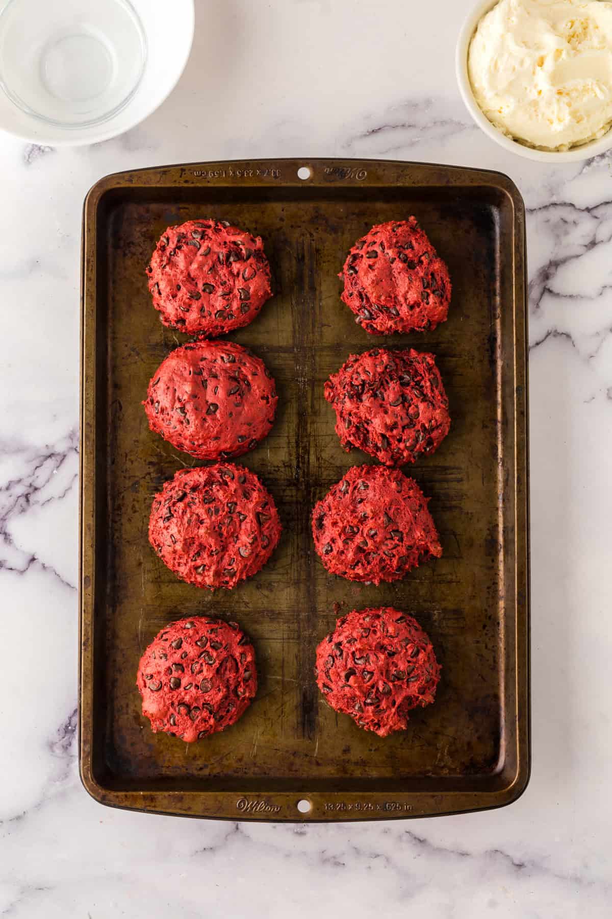 red velvet whoopee pie dough balls laid out on a baking dish.