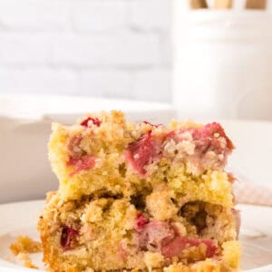 square portion of rhubarb crumble served on a round white plate.